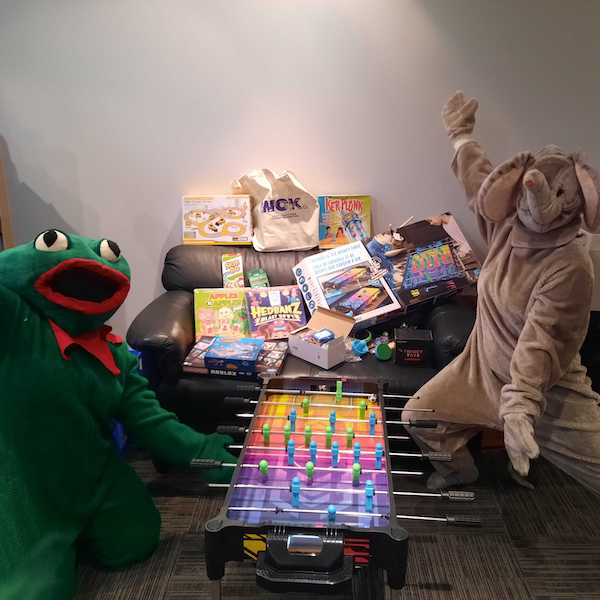Taylor and Dominique dressed up in a frog and elephant costume, showing off the toys and games that were gifted by WCK supporters for City Camp.