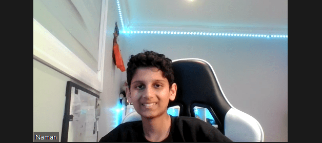 Naman sitting in a seat looking at his computer screen and smiling