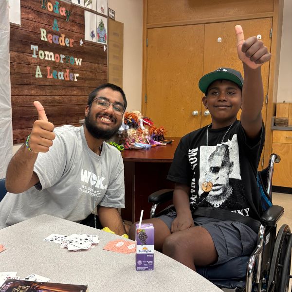 City Camp Volunteer smiling with a camper and giving the camera the thumbs-up. 