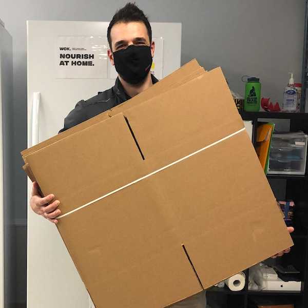 Jeff from Boxmaster in the WCK office, wearing a face mask and holding boxes he has delivered