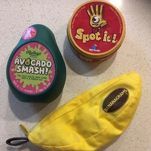 A photo of three handy travel-sized games: Spot It, Avocado Smash, and Bananagrams