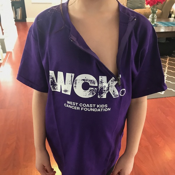 A close up photo of a child wearing a purple WCK Port Shirt with the zipper undone. The child's head is not in the photo.